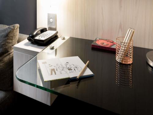 a glass desk with a book and a pen on it at ibis Sydney Barangaroo in Sydney