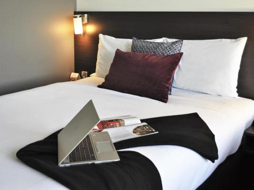 a laptop computer sitting on top of a bed at ibis Melbourne - Glen Waverley in Glen Waverley