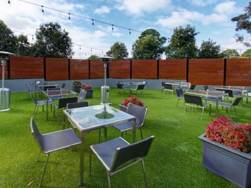 a patio with tables and chairs on the grass at ibis Melbourne - Glen Waverley in Glen Waverley