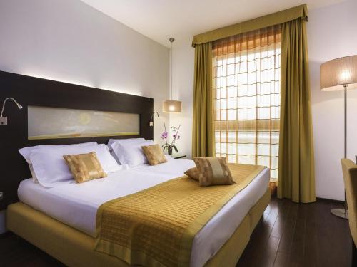 a bedroom with a large bed and a window at Hotel Mercure Siracusa in Siracusa
