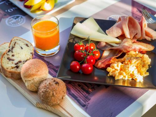 a plate of breakfast food with a glass of orange juice at Hotel Mercure Siracusa in Siracusa