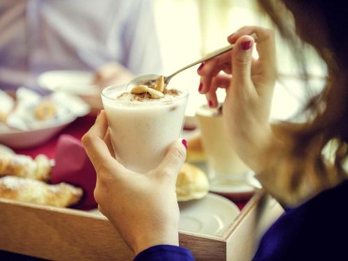 a woman is holding a drink with a spoon at Hotel Mercure Siracusa in Siracusa