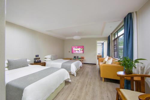 a hotel room with two beds and a couch at 铂曼智慧酒店-张家界国家森林公园门票站店 in Zhangjiajie