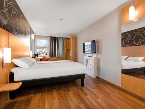 a hotel room with two beds and a flat screen tv at ibis Brighton City Centre - Station in Brighton & Hove