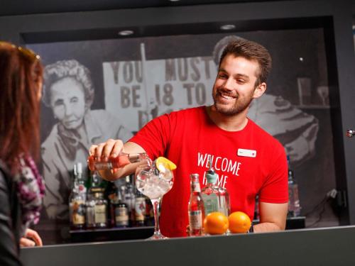 a man standing at a bar making a drink at ibis Brighton City Centre - Station in Brighton & Hove