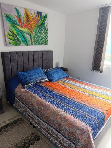 a bed with two pillows and a painting on the wall at Apartaestudio al norte de Armenia in Armenia