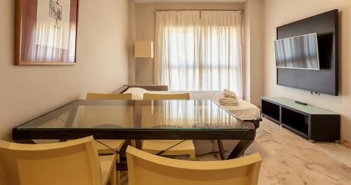 a living room with a glass table and chairs at Apartamentos Vértice Bib Rambla in Seville