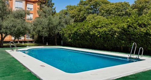 a swimming pool in a yard with trees and a building at Apartamentos Vértice Bib Rambla in Seville