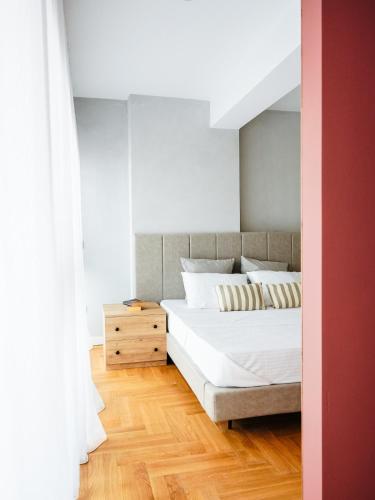 a bedroom with a large white bed and a wooden floor at Blush Studio at Rose in Prishtinë