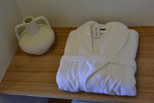 a white towel sitting on a table next to a vase at Lufra Beachside Hotel in Eaglehawk Neck