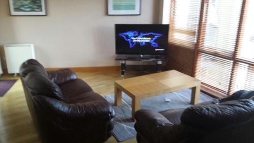 ein Wohnzimmer mit einem Sofa, einem Tisch und einem TV in der Unterkunft Foley Street Apartment in Dublin