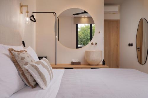 a bedroom with a white bed and a mirror at Avia in Corfu