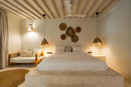 a bedroom with a large white bed and a couch at Seconda Stella Romantic Hideaway in Jambiani