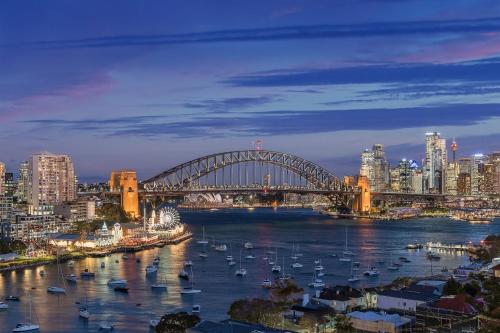 a bridge over a river with boats in a city at Panoramic Sydney Harbour Views from Luxury 1-Bedroom Apartment in McMahons Point in Sydney
