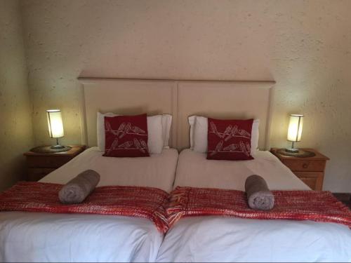 a bedroom with a bed with two pillows and two lamps at Mount Festiva Lodge in Akasia