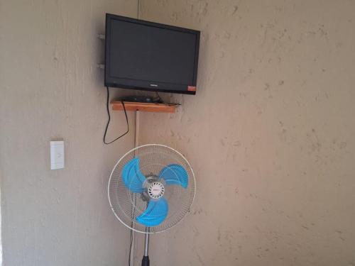 a fan hanging on a wall next to a television at Mount Festiva Lodge in Akasia