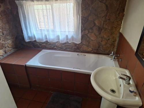a bathroom with a bath tub and a sink at Mount Festiva Lodge in Akasia