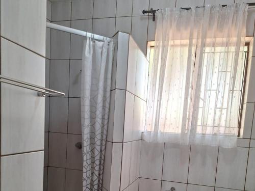 a shower with a shower curtain and a window at Mount Festiva Lodge in Akasia