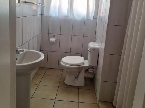 a small bathroom with a toilet and a sink at Mount Festiva Lodge in Akasia