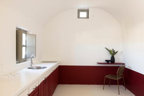 a bathroom with a sink and a chair at Neema Maison Finikia Santorini in Oia