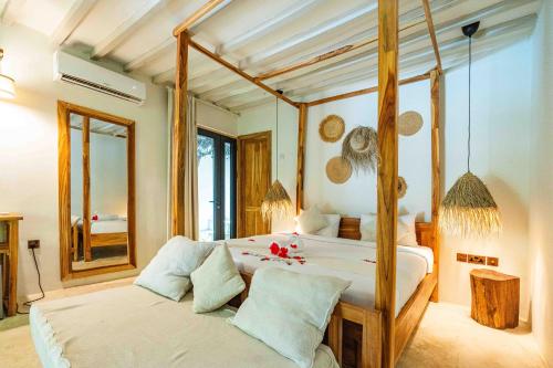 a bedroom with a four poster bed and a mirror at Seconda Stella Romantic Hideaway in Jambiani