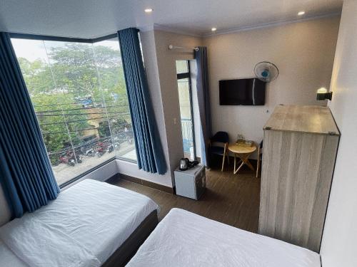 a hotel room with a bed and a large window at NA NI in Da Lat