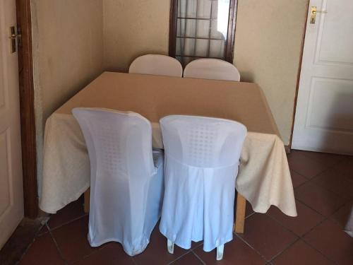 a table with two white chairs sitting at a table at Mount Festiva Lodge in Akasia