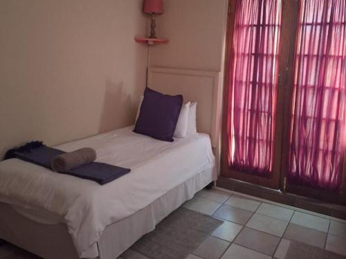 a small bed in a room with red lights at Mount Festiva Lodge in Akasia