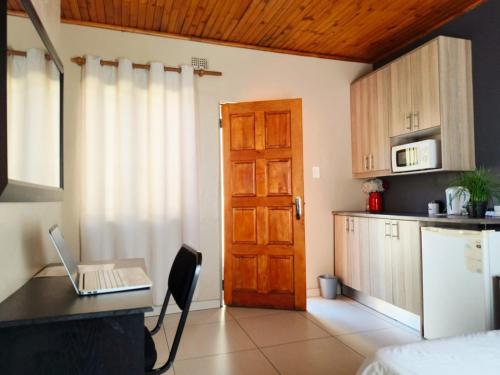 a kitchen with a door and a laptop on a table at Tokelo Guesthouse Emalahleni in Witbank