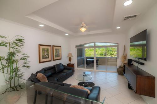 a living room with a couch and a tv at Colina 5D 3 bdr Garden View in Los Suenos in Herradura