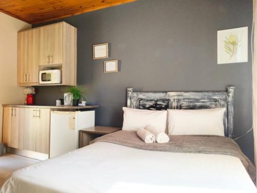 a bedroom with a white bed and a kitchen at Tokelo Guesthouse Emalahleni in Witbank