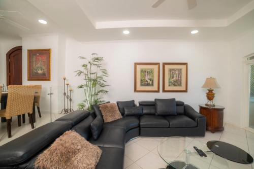 a living room with a black leather couch at Colina 5D 3 bdr Garden View in Los Suenos in Herradura