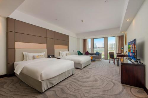 花都にあるZhengsheng Honggu Hotel - Guangzhou Sunac Cultural Tourism City Huadu Plazaのベッド2台とテレビがあるホテルの部屋