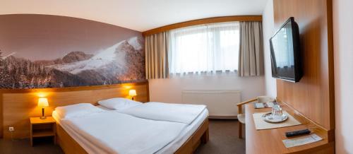 a hotel room with a bed and a flat screen tv at Hotel FIS in Štrbské Pleso