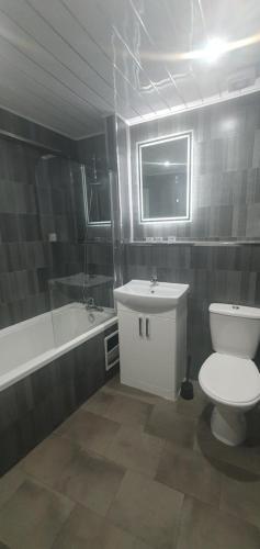 a bathroom with a toilet and a sink and a tub at South Beach Kings Promenade Hotel in Blackpool