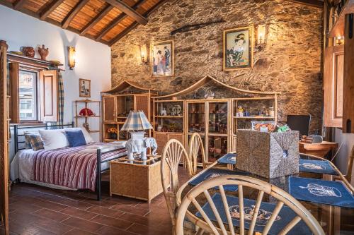 une chambre avec un lit et un mur en pierre dans l'établissement Villa Casas de São Francisco da Chã, à Góis