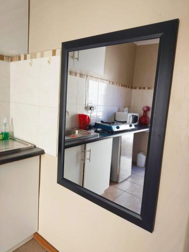 a mirror hanging on a wall in a kitchen at Tokelo Guesthouse Emalahleni in Witbank