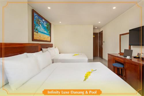 a bedroom with two beds and a desk and a television at Infinity Luxe Danang & Pool in Da Nang