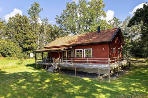 a small red house with a porch in a field at KAL642-Fagerhult-Solaeng-203 in Fagerhult