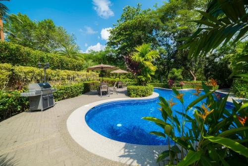 a swimming pool in a garden with trees at Veranda 3B 2 bdr Garden View in Los Suenos in Herradura