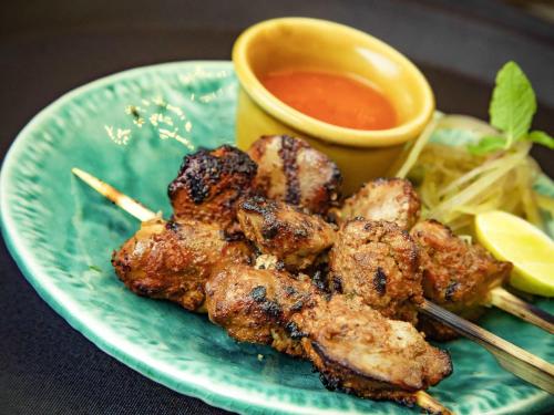 a plate of food with meat and dipping sauce at ibis Bengaluru City Centre - An Accor Brand in Bengaluru