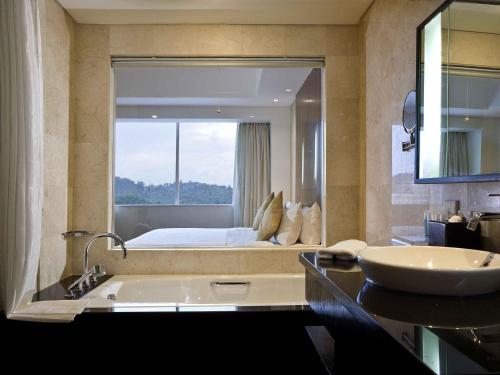 a bathroom with a bed and a tub and a sink at Novotel Balikpapan in Balikpapan