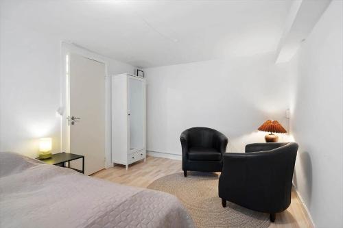 a bedroom with a bed and two chairs and a lamp at FY385-Nyborg-Kronprinsensgade-1-st in Nyborg