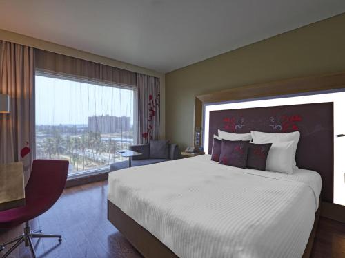 a bedroom with a large bed and a large window at Novotel Bengaluru Outer Ring Road in Bengaluru