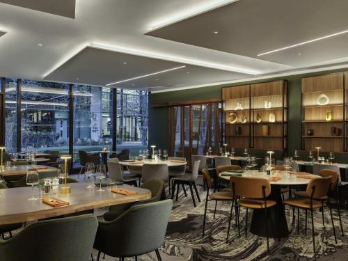 a dining room with tables and chairs and windows at Novotel London Paddington in London