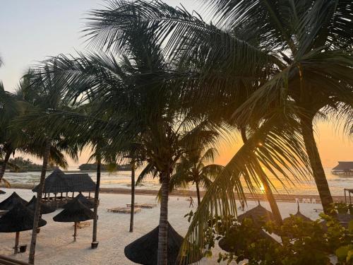 a beach with umbrellas and palm trees and the ocean at TOA Hotel & Spa Zanzibar in Pongwe