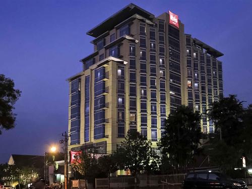 a tall building with a sign on top of it at Hotel Ibis Semarang Simpang Lima in Semarang