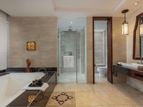 a bathroom with a tub and a sink and a toilet at Pullman Sanya Yalong Bay Villas & Resort in Sanya