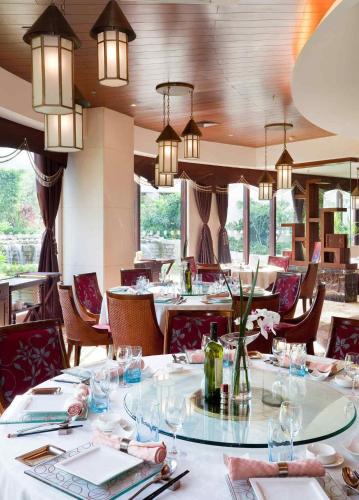 a dining room with tables and chairs and chandeliers at Pullman Sanya Yalong Bay Villas & Resort in Sanya