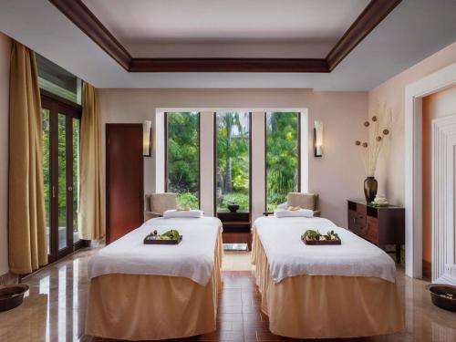 two beds in a room with large windows at Pullman Sanya Yalong Bay Villas & Resort in Sanya